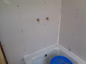 Shower water feeds behind the tiles in a bathroom wall