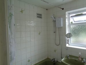 Old bathroom with electric shower on the window wall in Coventry